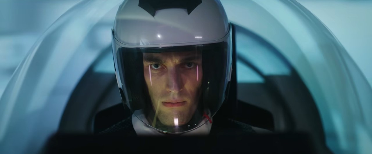 A pilot in a white helmet sits in a cockpit in Apotheosis