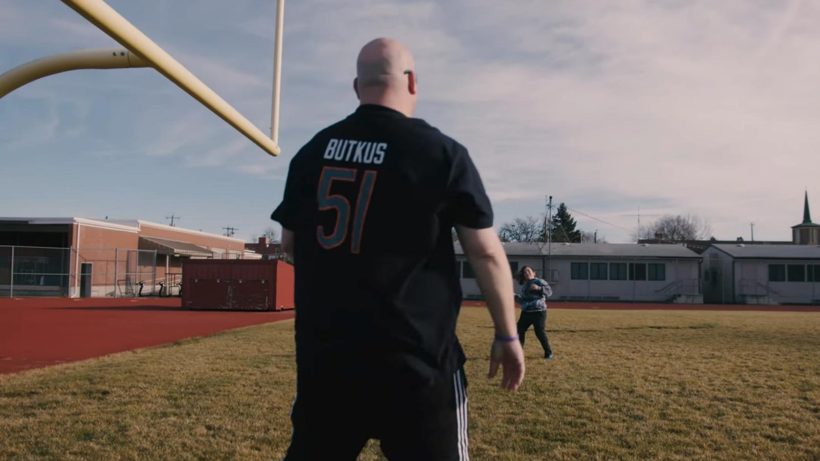 A collector in a Butkus jersey stands under a football goalpost in In Search of Boozers and Schmucks