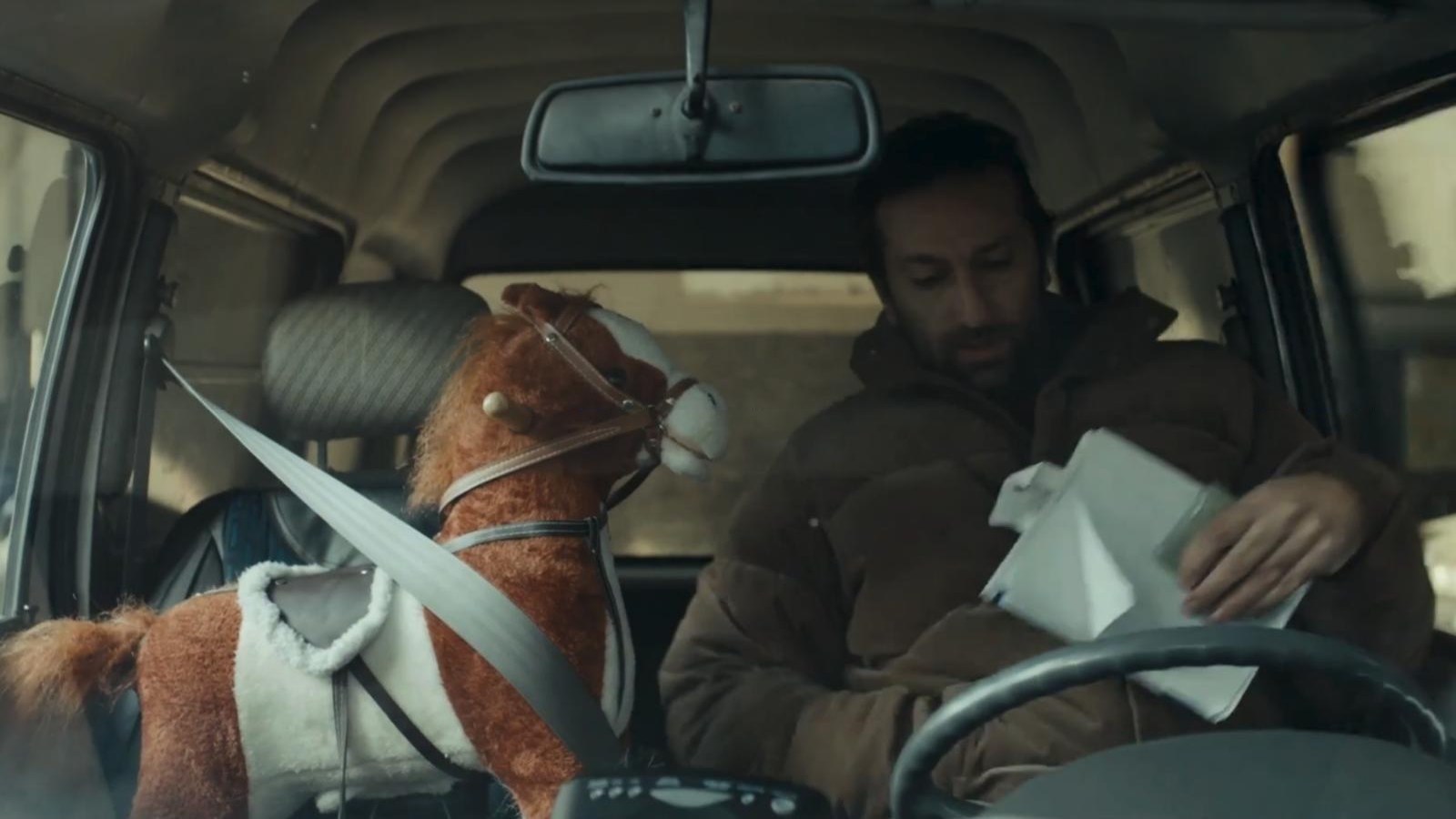 A rocking horse buckled into the passenger seat of a car in Sticker