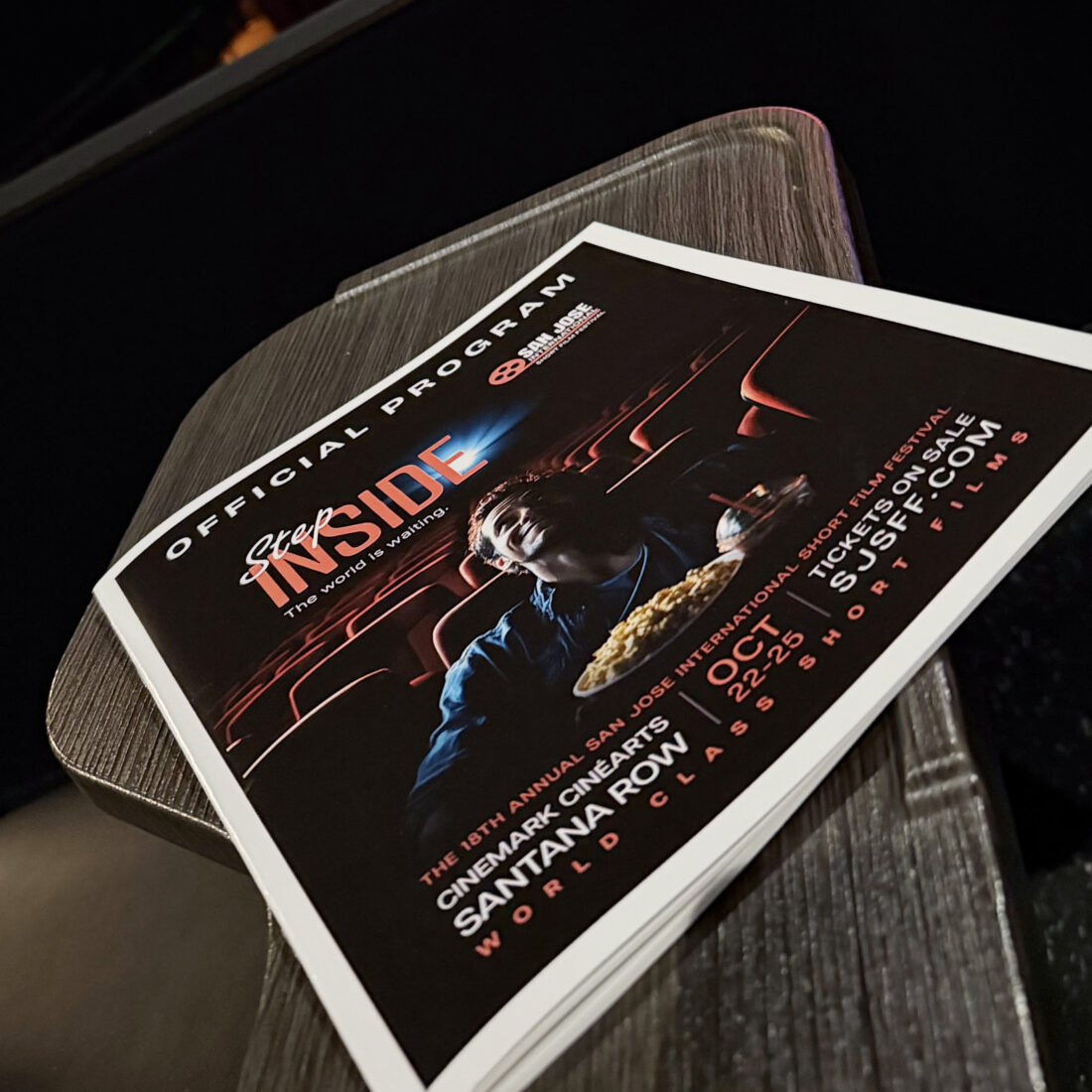 The official program for the 2026 San Jose International Short Film Festival, with the “Step Inside” cover, resting on a theater seat armrest