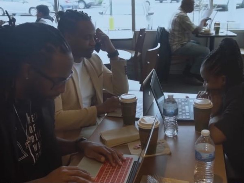 People working on laptops in a café in Generation Impact: The Coder