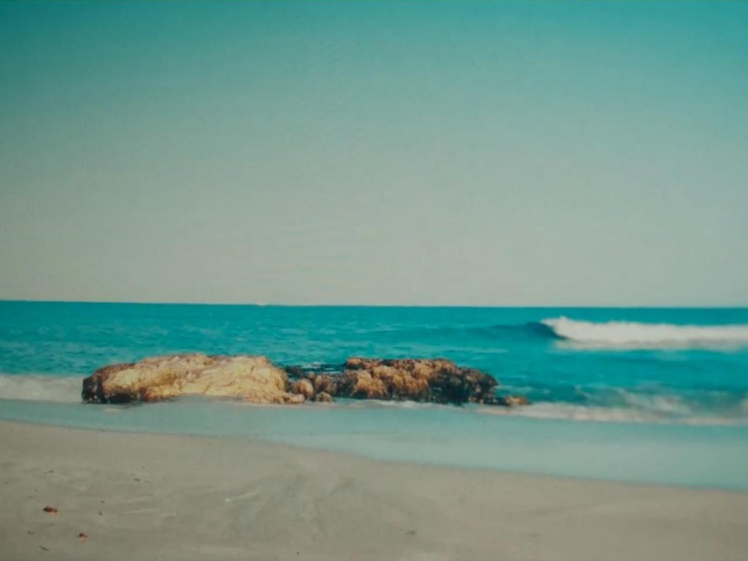 A sunlit beach with rocks and waves in Rachels Don’t Run