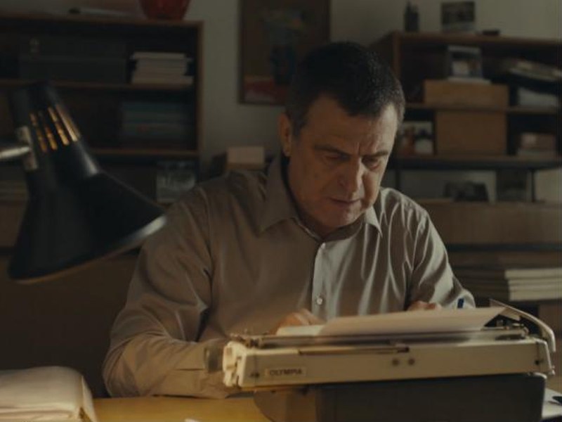 A man types at an old typewriter in an office in Sticker