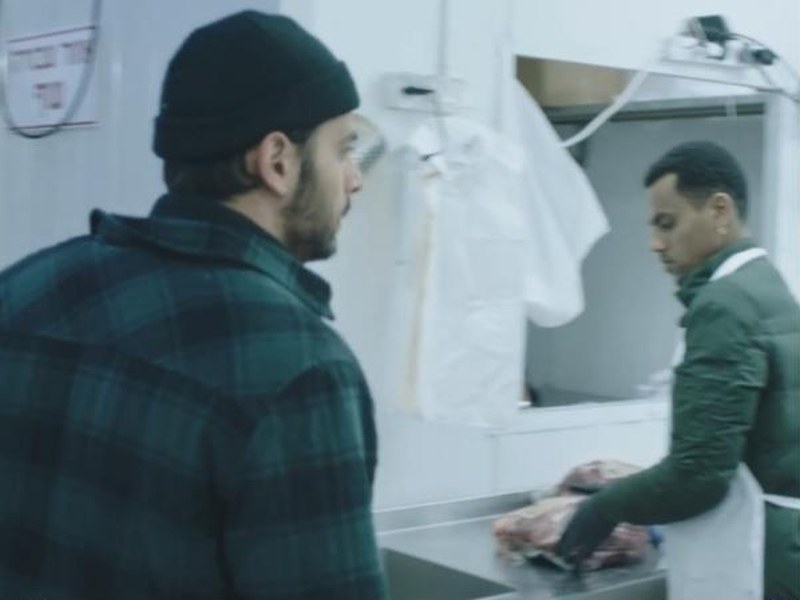 A man watches a butcher at work in White Eye