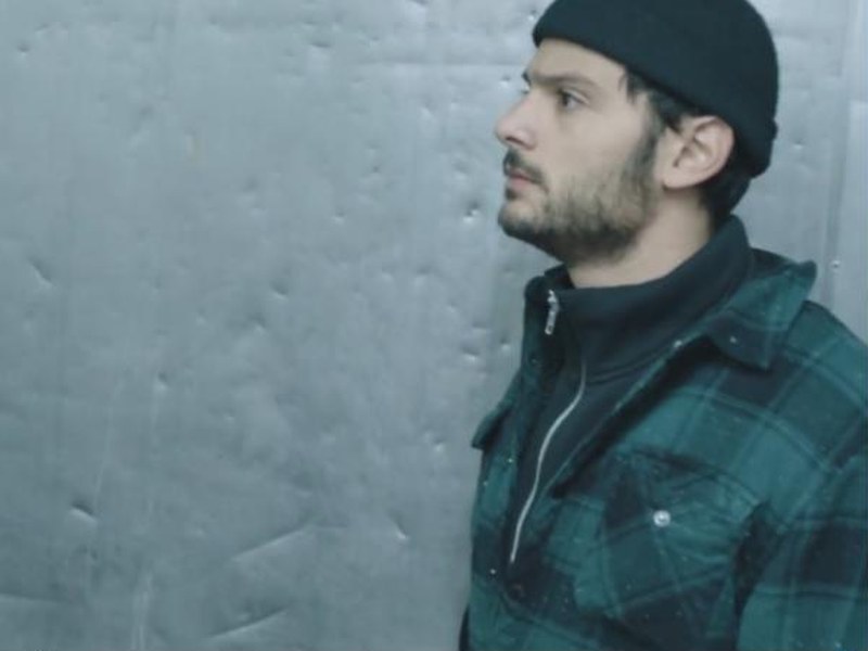 A man in a beanie stands in a walk-in freezer in White Eye